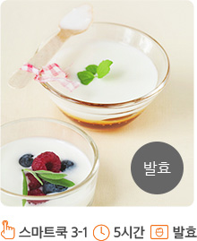베이지색의 테이블 위로 유리그릇들이 위치해 있습니다. 상단의 유리그릇과 하단의 유리그릇에 각각 요구르트가 담겨져 있습니다. 상단의 유리그릇에는 요구르트 위에 녹색 이파리와 리본으로 끝부분을 장식한 숟가락이 올려져 있습니다. 하단의 유리그릇 위에는 녹색 이파리와 딸기, 블루베리들이 올려져 있습니다.화면의 오른쪽 하단에는 회색 원안에 “발효” 라고 적혀져 있습니다.