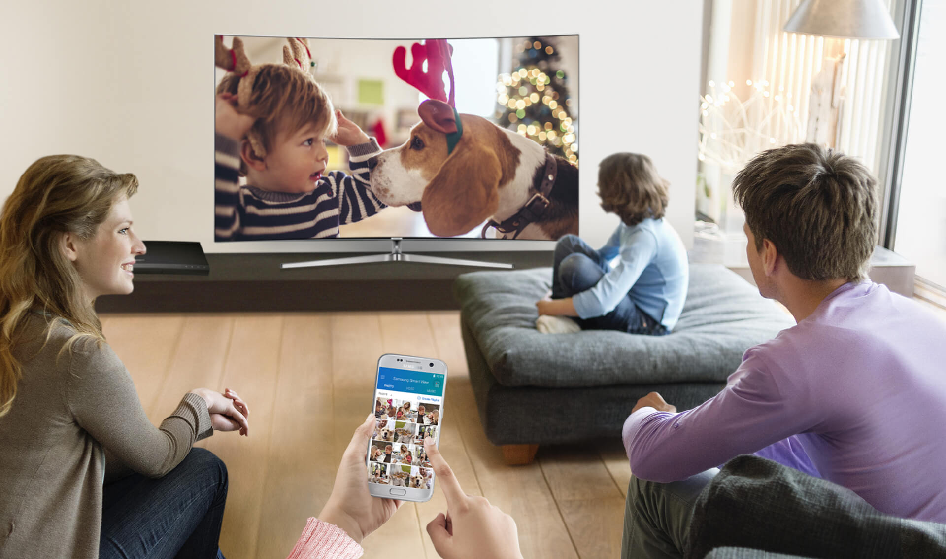 A happy family is watching a photo from a mobile devices directly to Samsung SUHD TV.